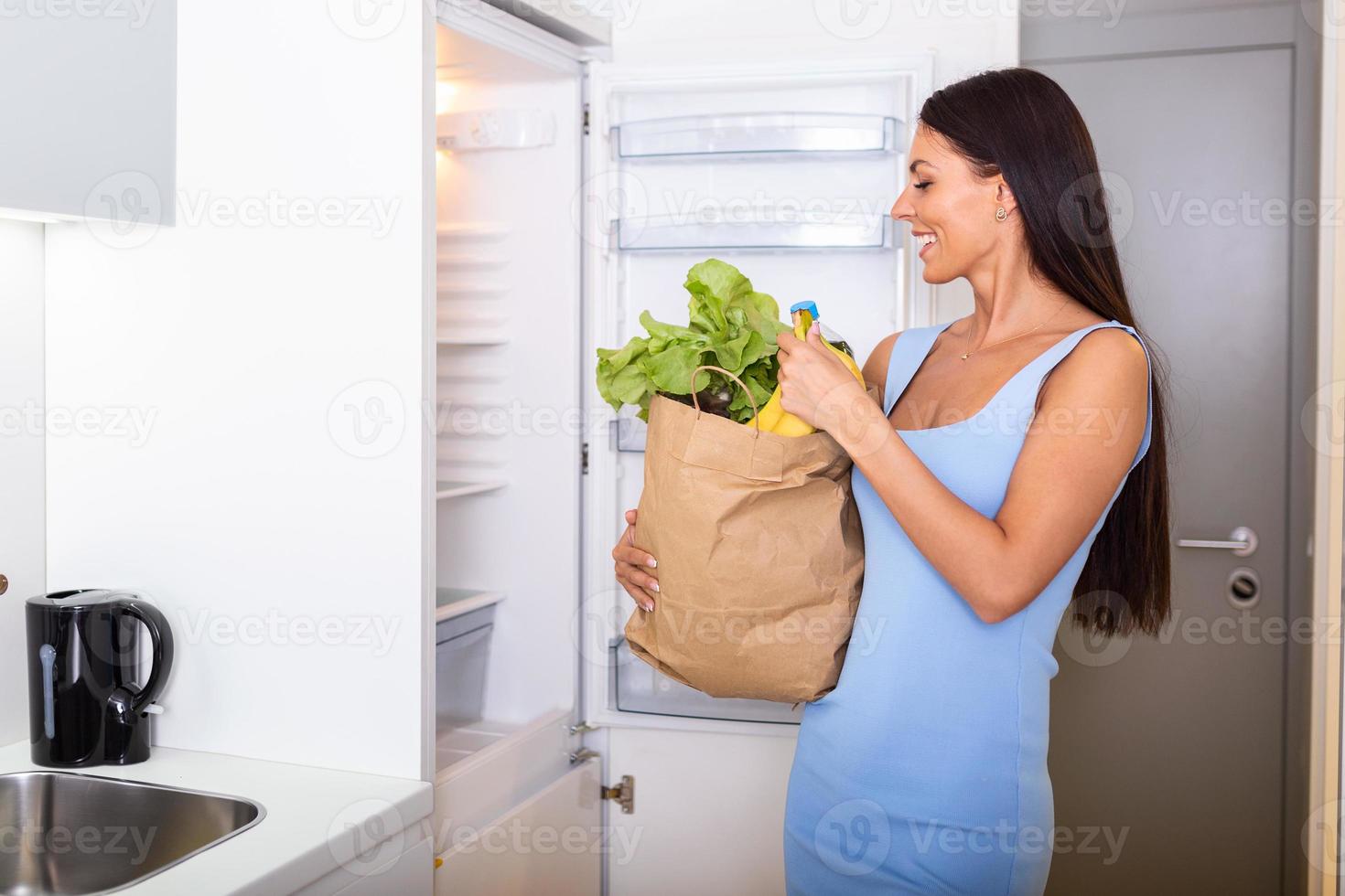 salutare mangiare concetto. dieta. bellissimo giovane donna vicino il frigo con salutare cibo. frutta e verdure nel il frigorifero. vegano cibo foto