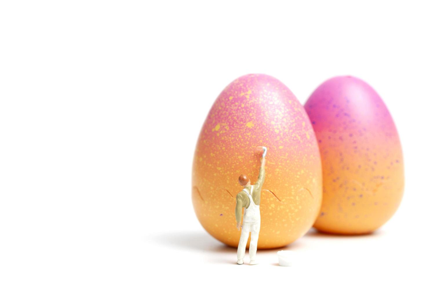 persona in miniatura pittura uova di Pasqua per il giorno di Pasqua su uno sfondo bianco foto