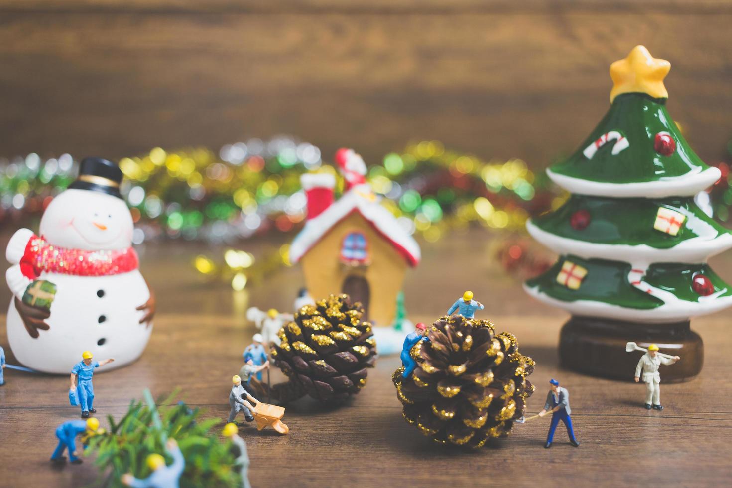 persone in miniatura che creano decorazioni natalizie su uno sfondo di legno foto