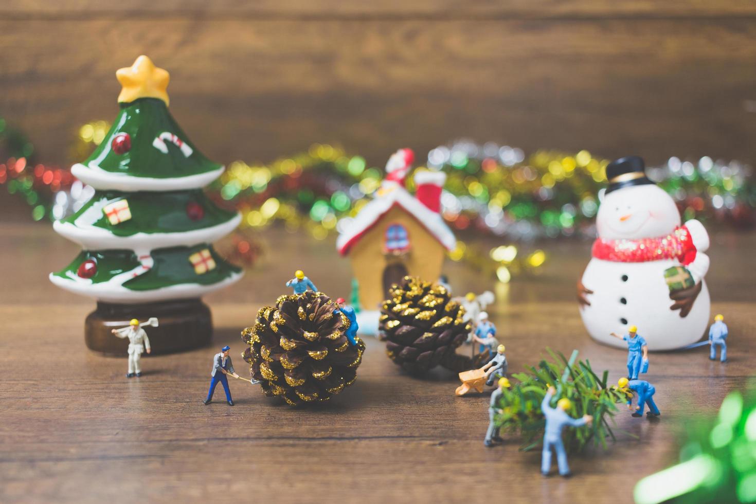 persone in miniatura che creano decorazioni natalizie su uno sfondo di legno foto