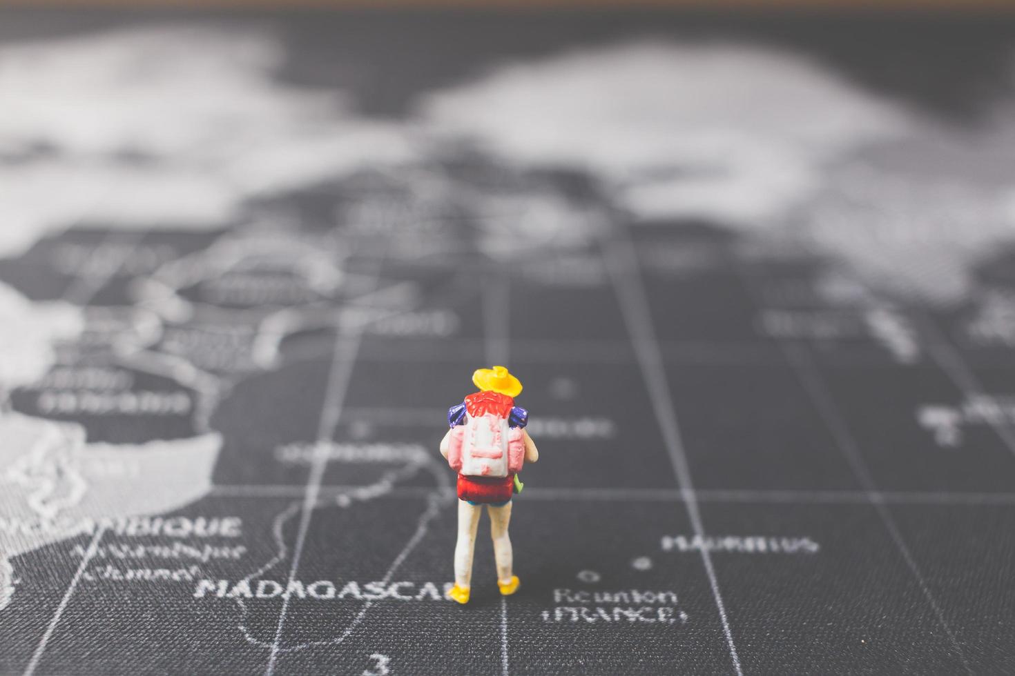 zaino in spalla in miniatura che cammina su una mappa del mondo, turismo e concetto di viaggio foto