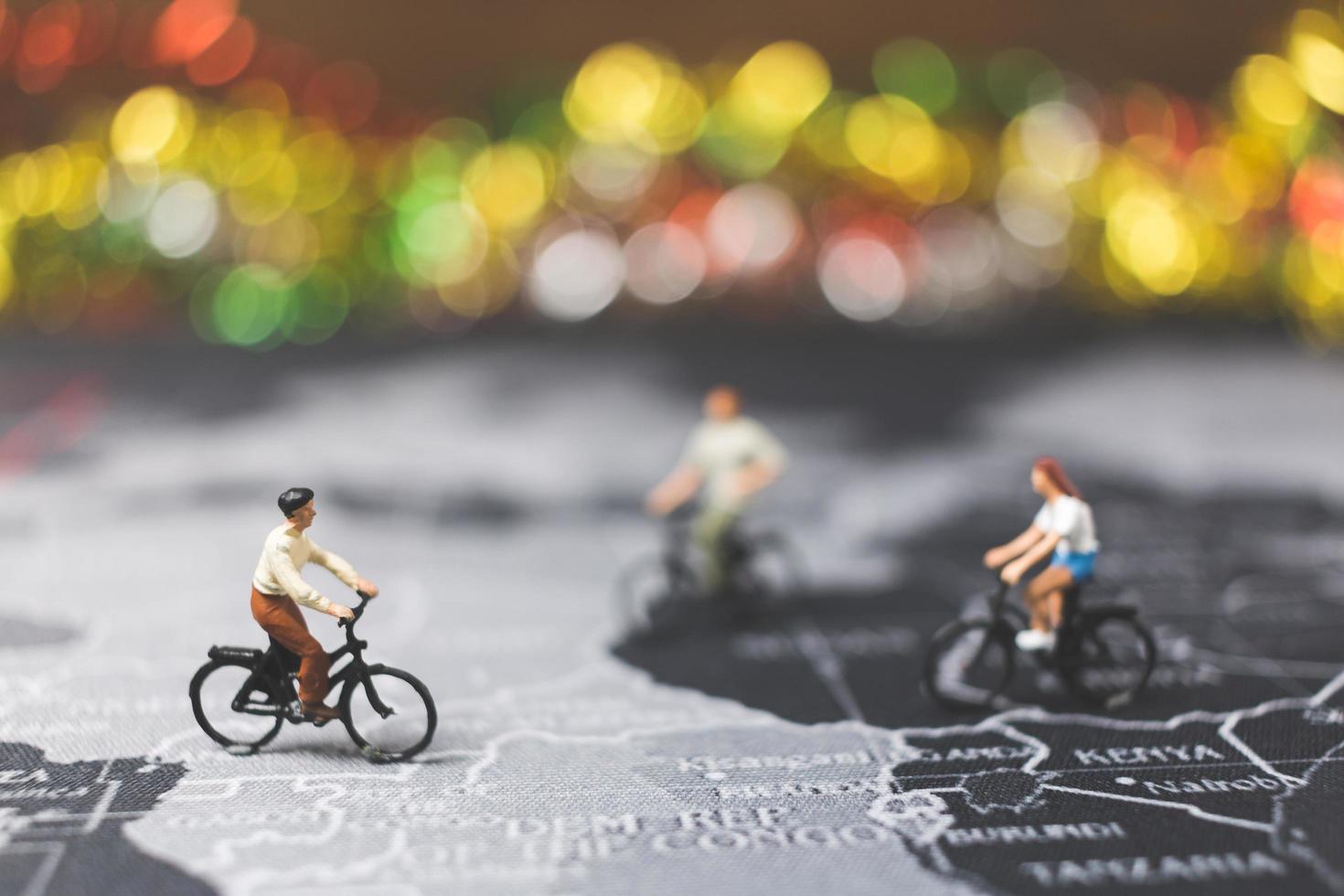 viaggiatori in miniatura in sella a una bicicletta su una mappa del mondo, viaggiando ed esplorando il concetto di mondo foto