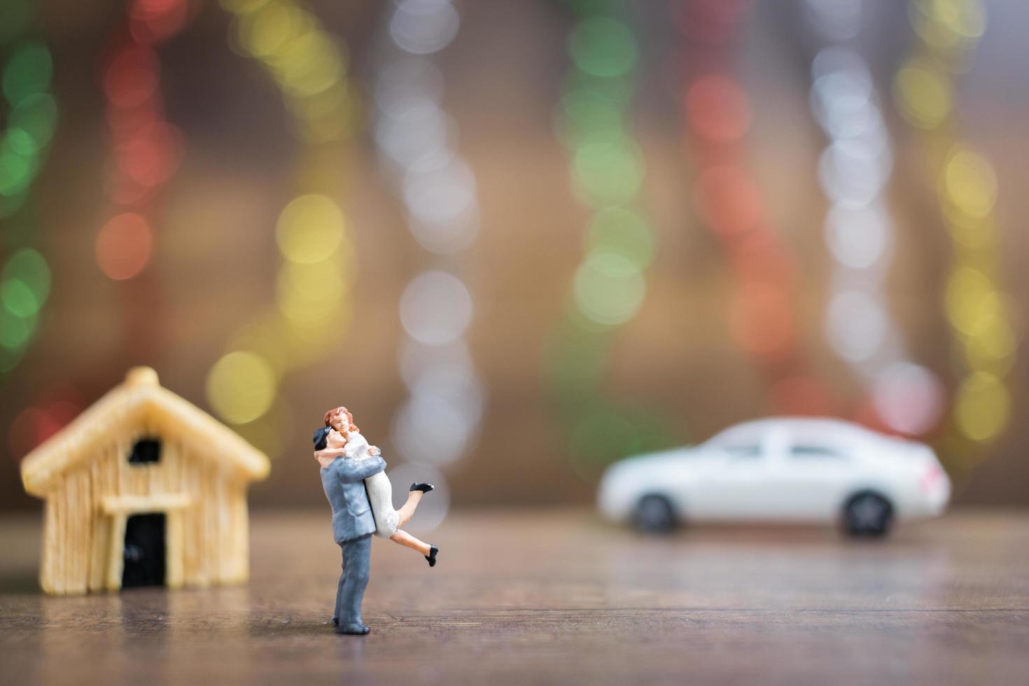 coppia in miniatura che abbraccia su un pavimento di legno con un colorato sfondo bokeh di fondo, concetto di famiglia di successo foto