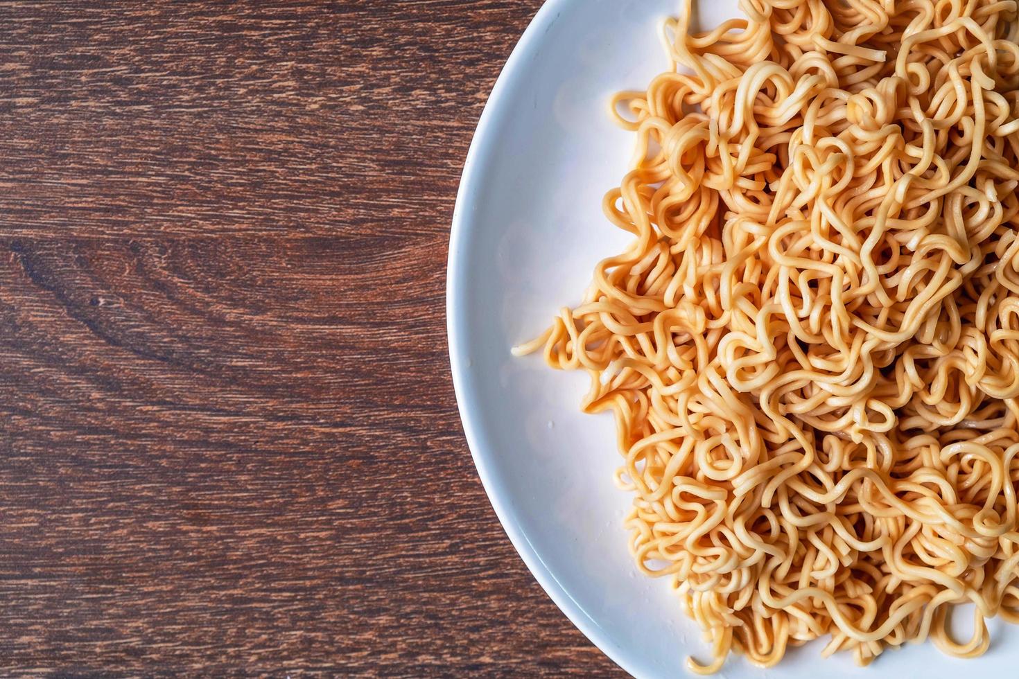 spaghetti istantanei su un piatto bianco su un tavolo di legno foto