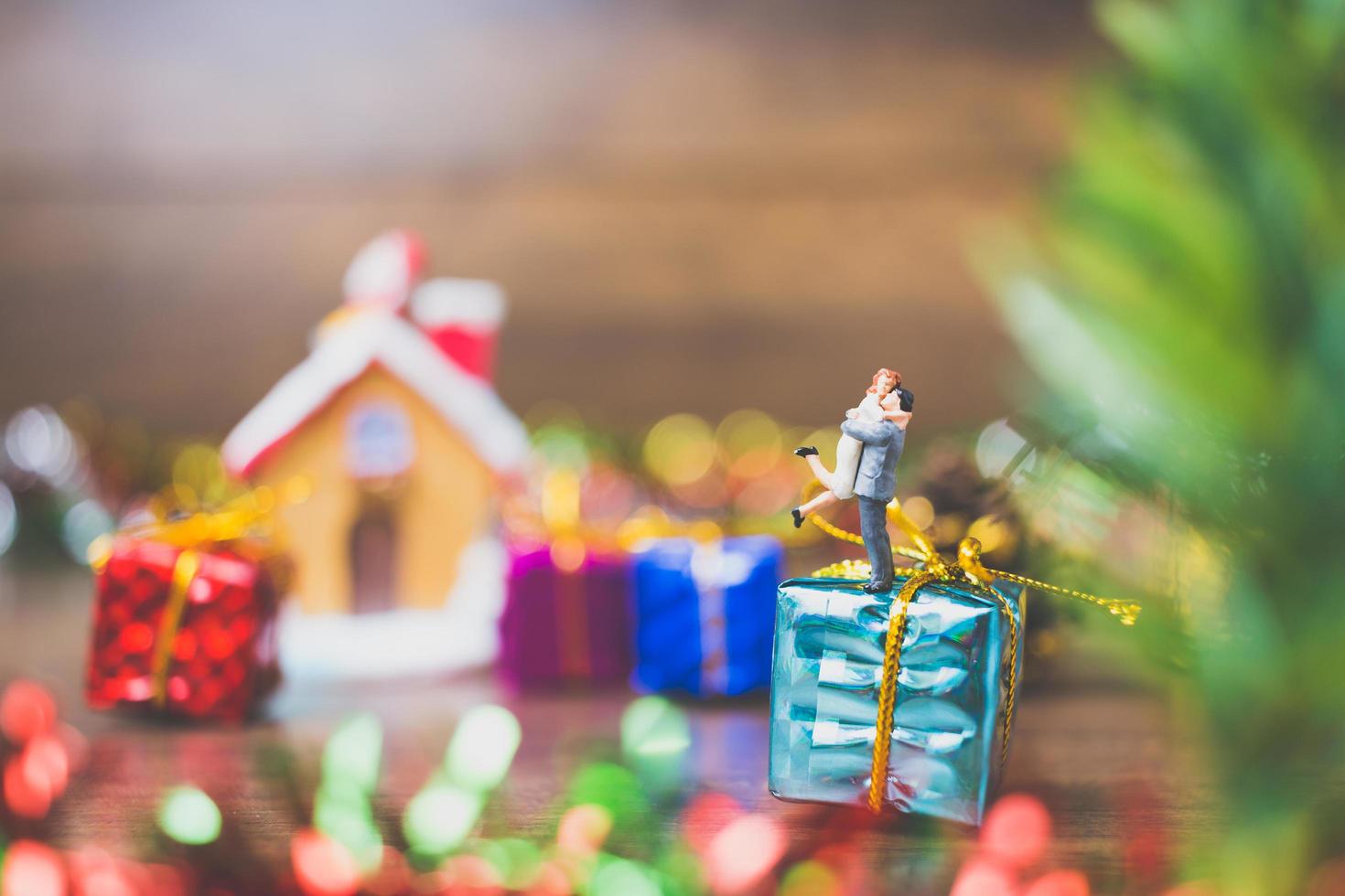 persone in miniatura su una confezione regalo con decorazioni natalizie in background foto