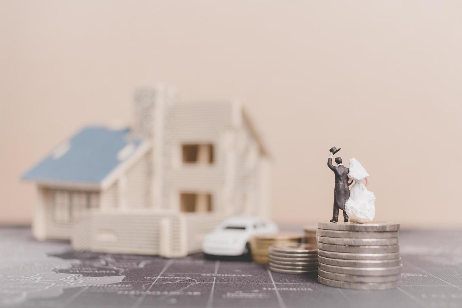 sposa e sposo in miniatura con monete davanti a una casa, concetto di famiglia di successo foto