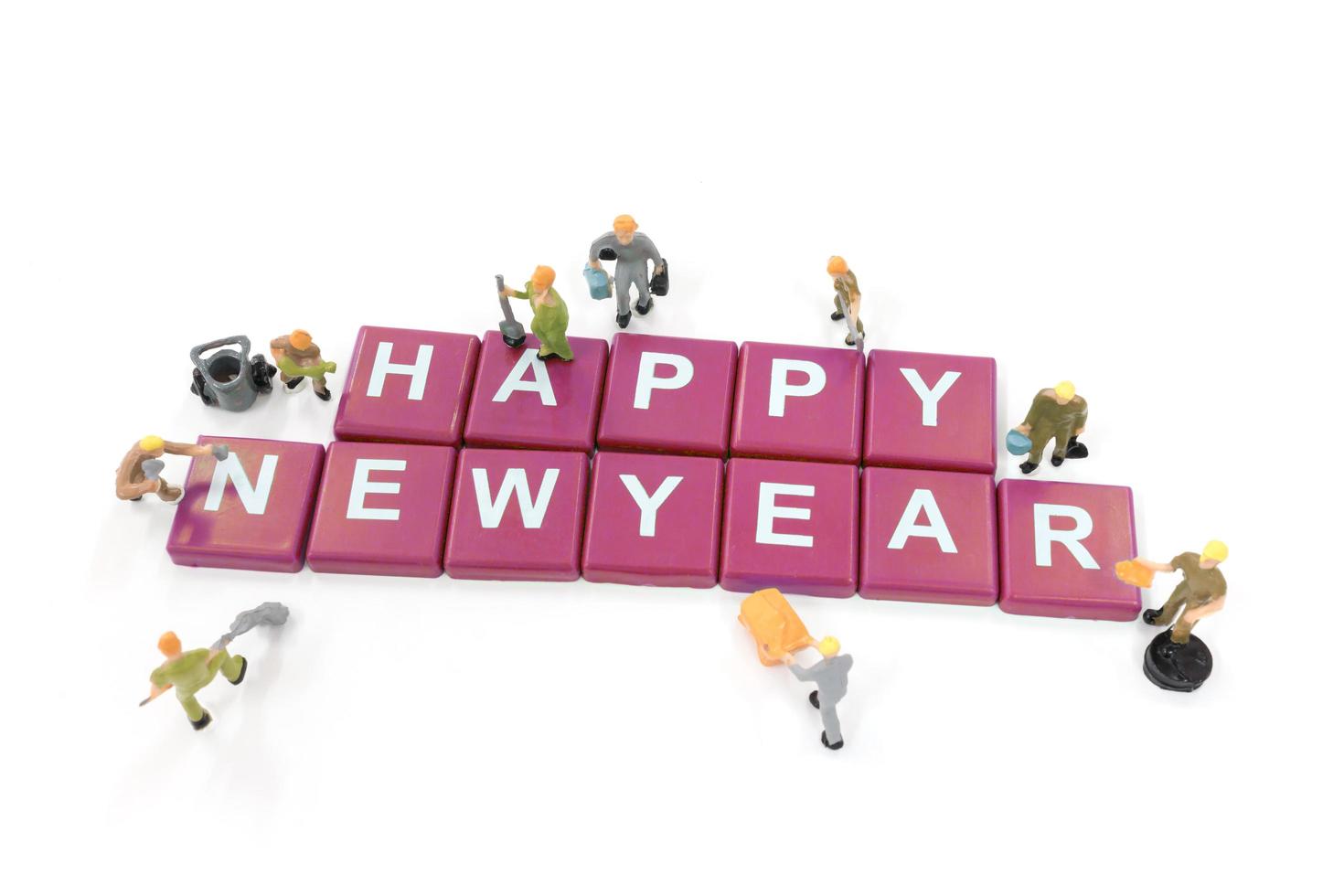 lavoratori in miniatura che costruiscono la parola felice anno nuovo su uno sfondo bianco foto