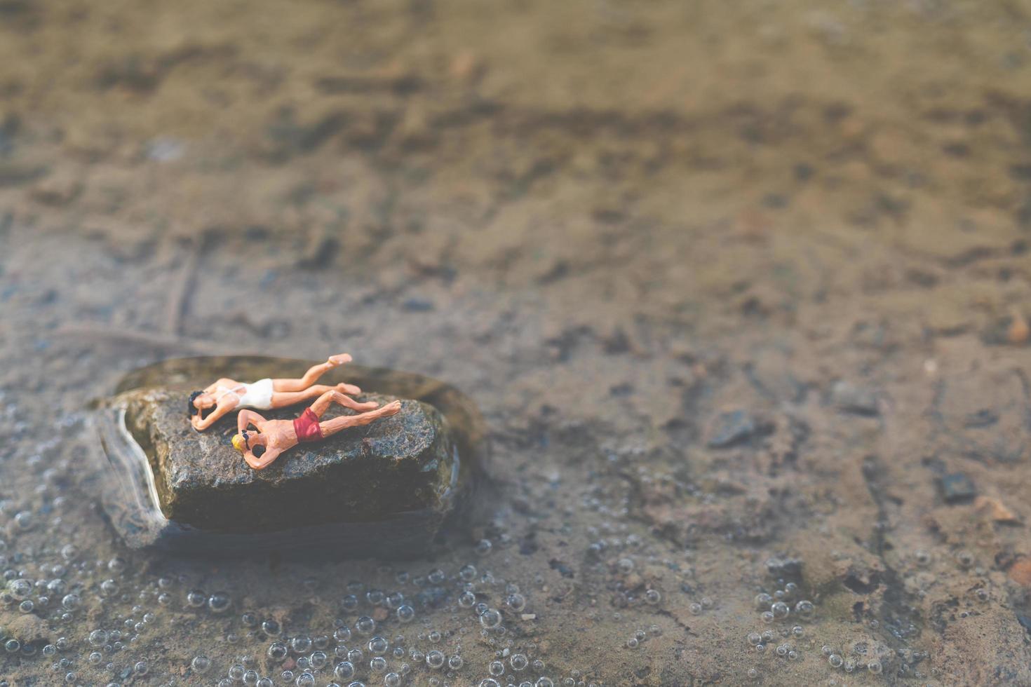 persone in miniatura che indossano costumi da bagno rilassante su una spiaggia, concetto di estate foto