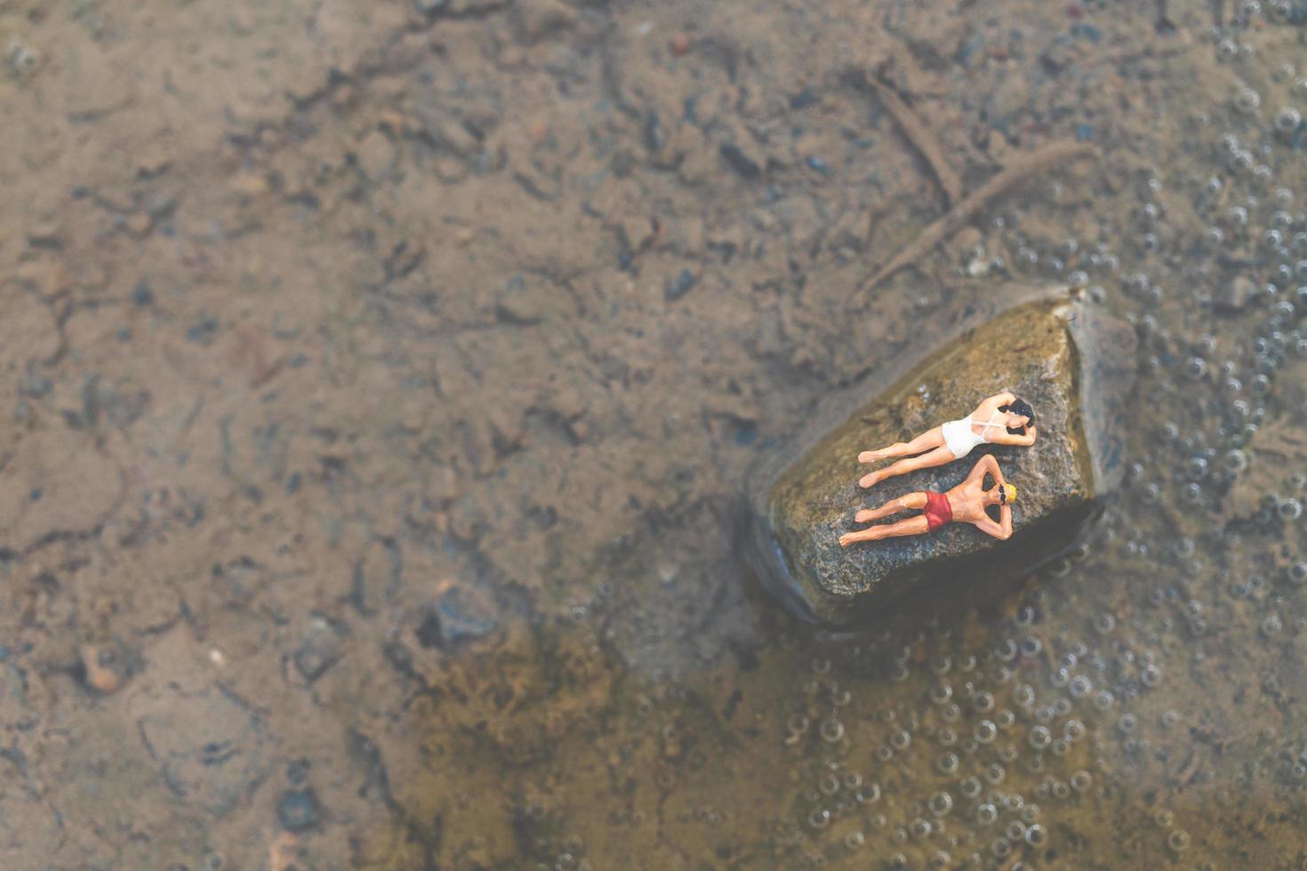 persone in miniatura che indossano costumi da bagno rilassante su una spiaggia, concetto di estate foto