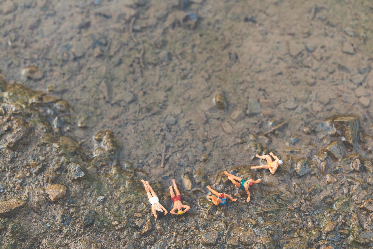 persone in miniatura che indossano costumi da bagno rilassante su una spiaggia, concetto di estate foto