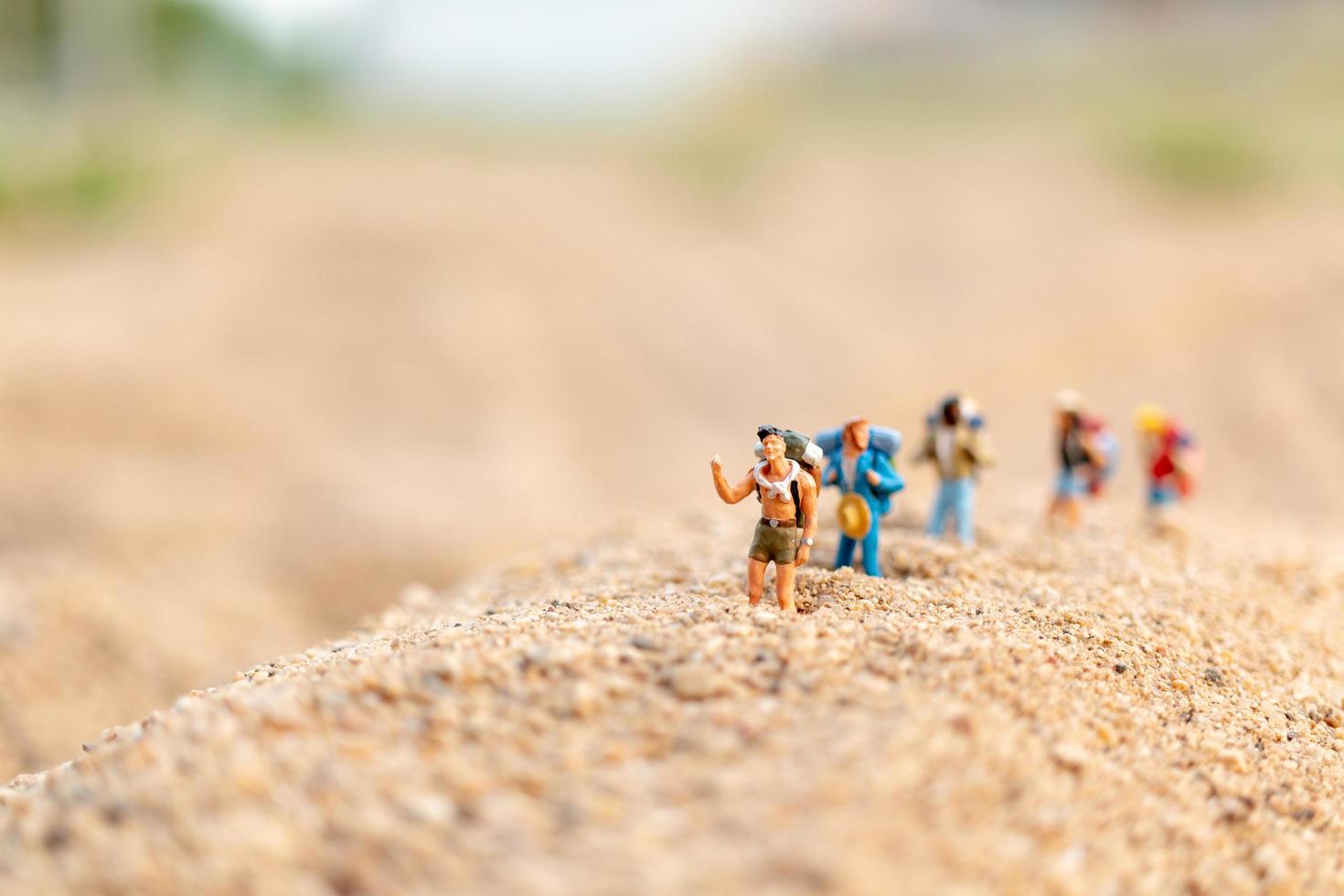 viaggiatori in miniatura con zaini che camminano sulla sabbia, viaggi e concetto di avventura foto