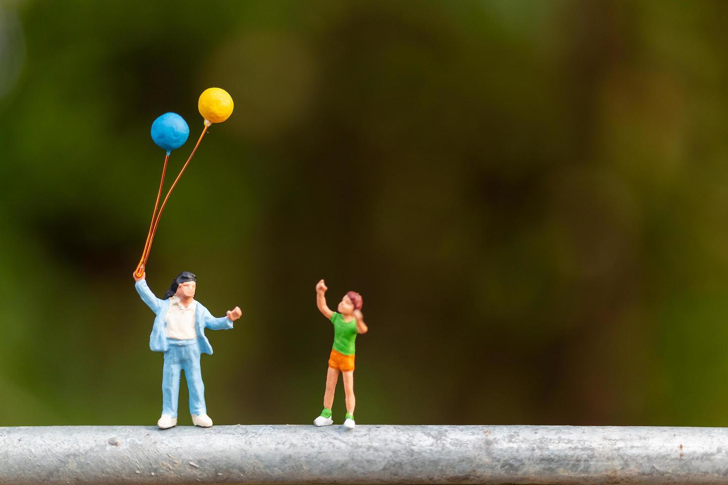famiglia in miniatura che tiene palloncini colorati, concetto di famiglia felice foto