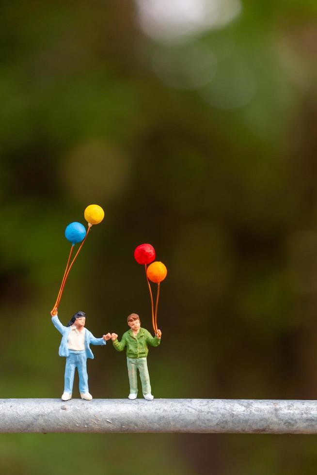 famiglia in miniatura che tiene palloncini colorati, concetto di famiglia felice foto