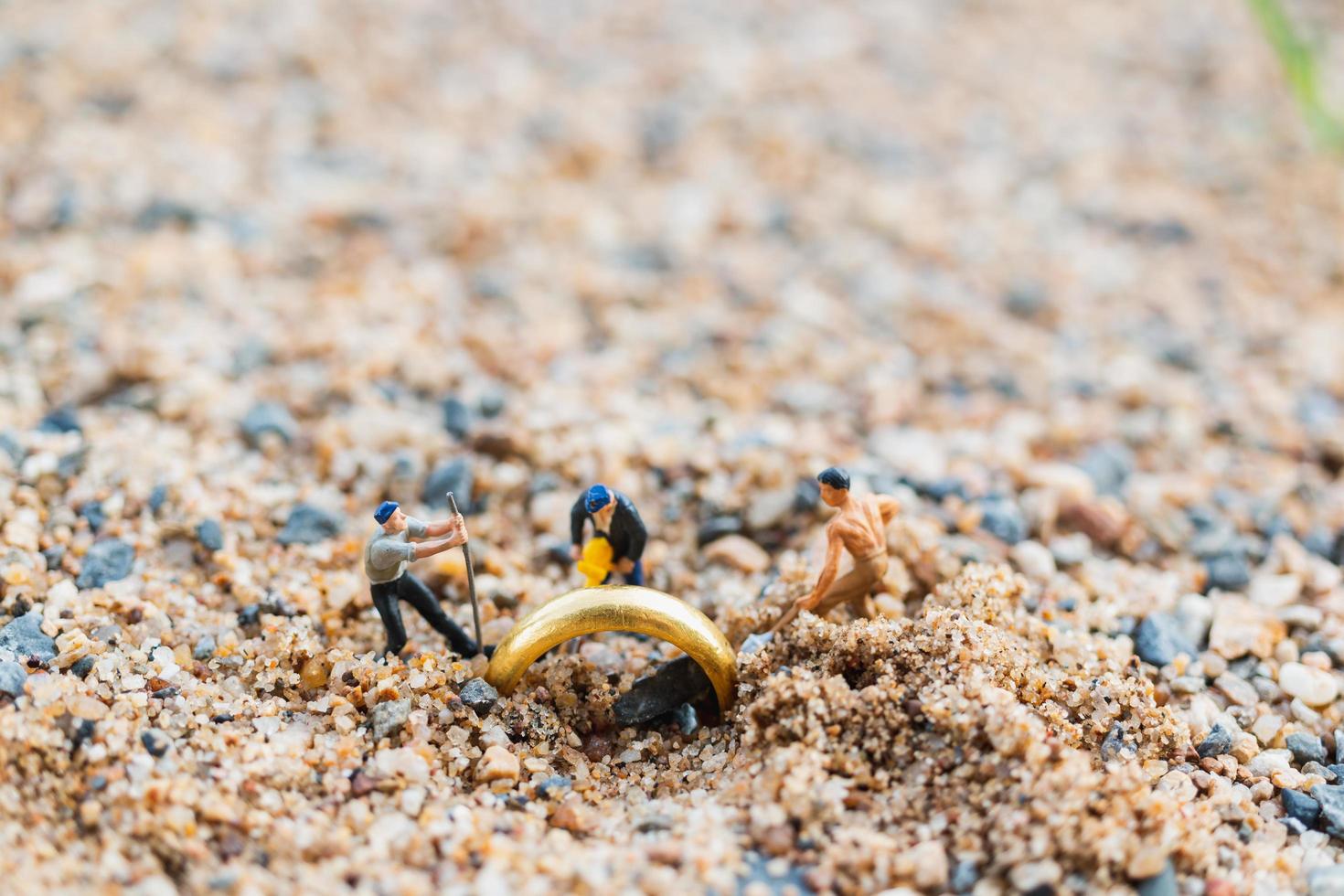 lavoratori in miniatura che scavano anelli d'oro nella sabbia, concetto di crescita aziendale foto