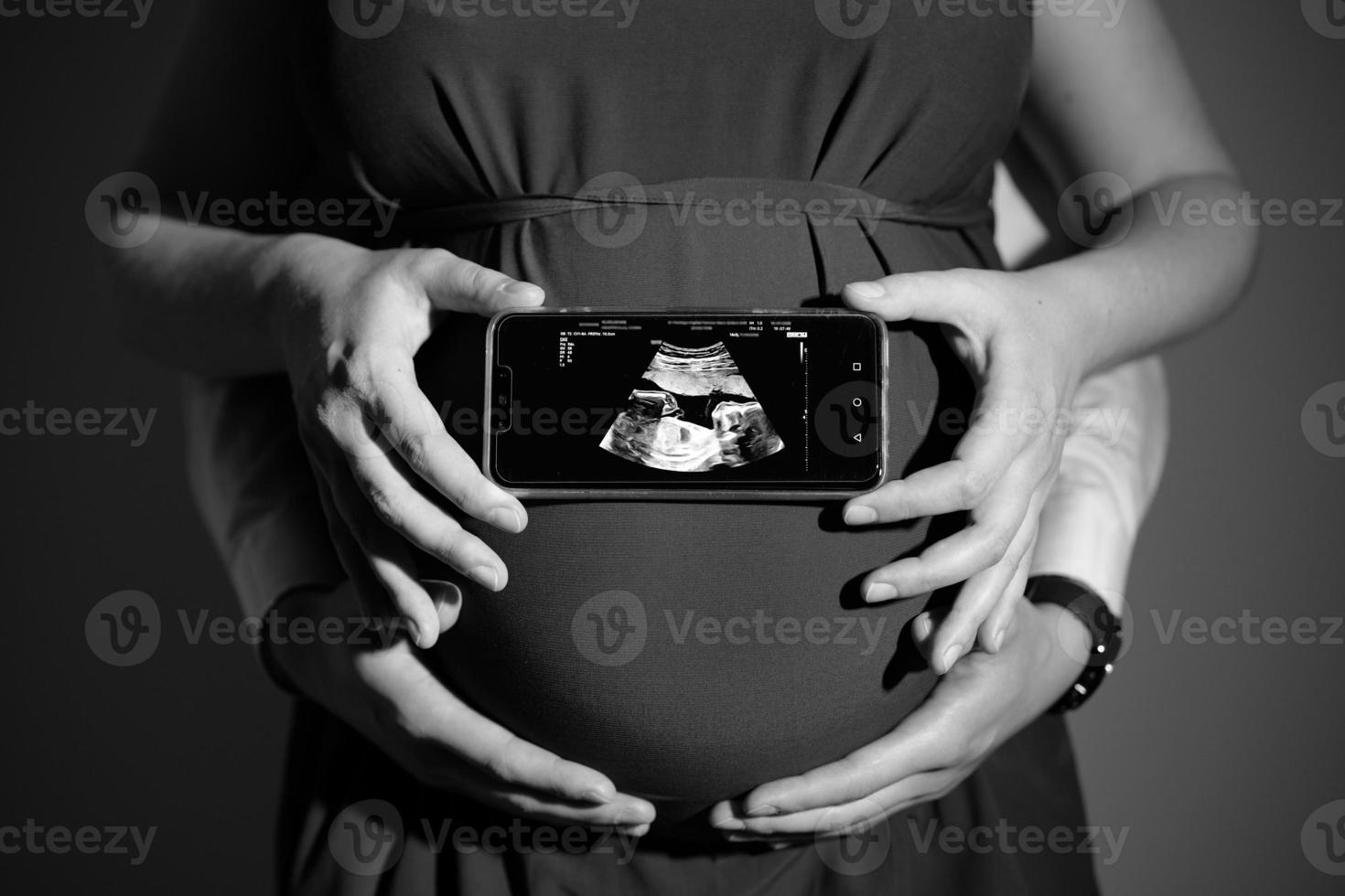 nero e bianca foto di il incinta donna Tenere il risultati di il del bambino ultrasuono medico immagini, con il mani di il marito Tenere il pancia