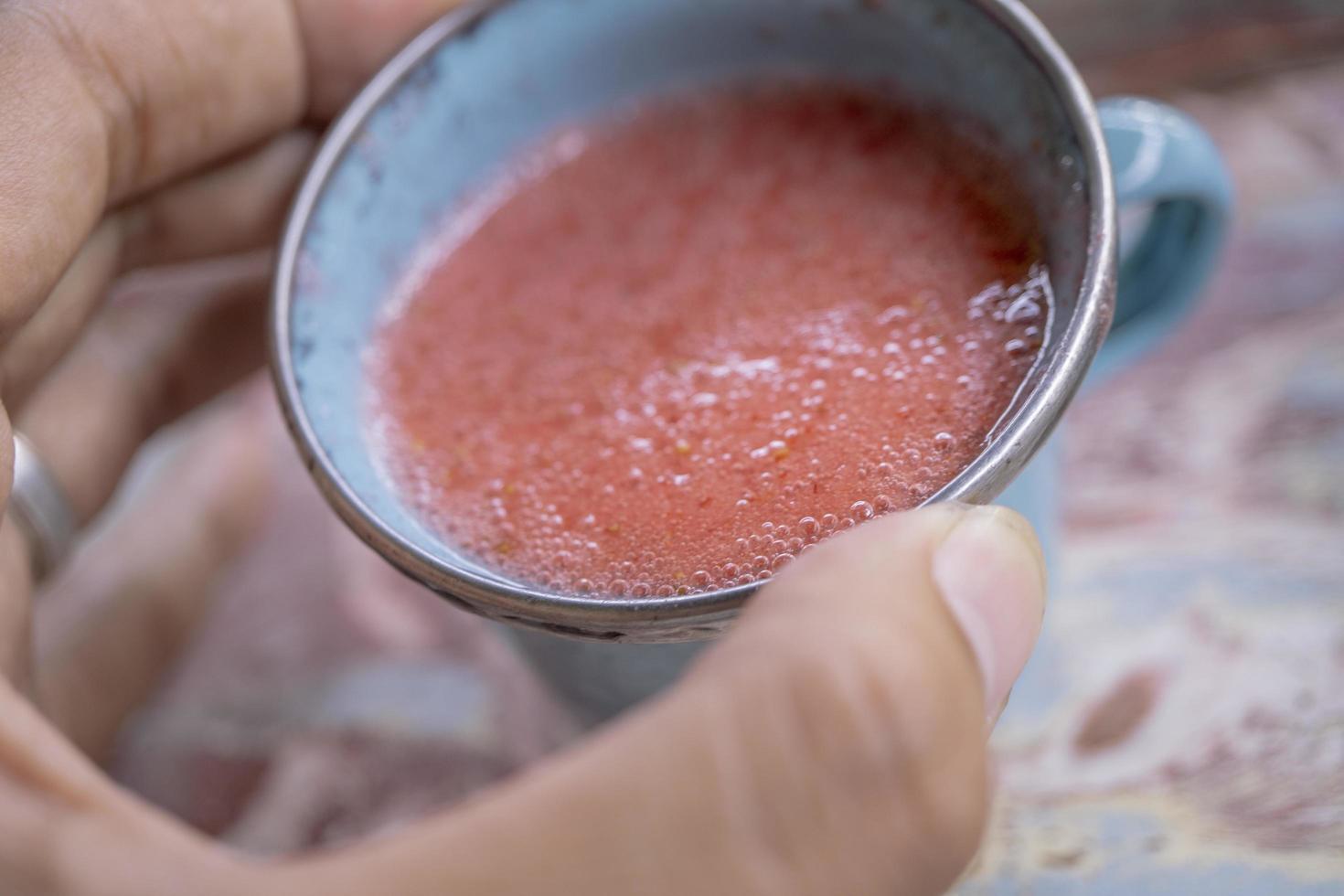 vicino su foto di fresco fragola succo su il blu tazza a il giardino negozio. il foto è adatto per uso per salutare bere, menù sfondo, e bevanda soddisfare media.