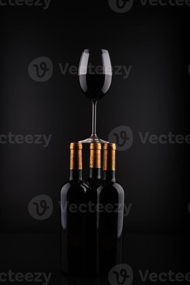bottiglia di vino e vetro con sfondo nero foto