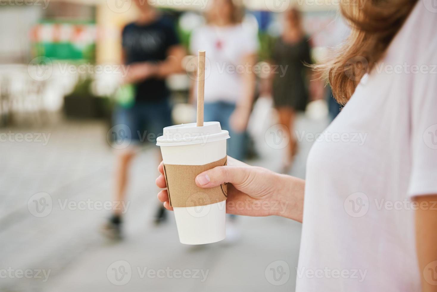 donna passeggiate a città strada con carta caffè tazza. foto