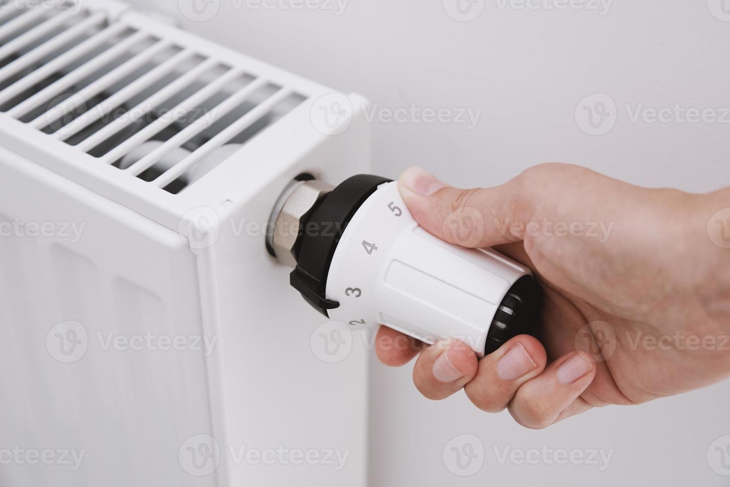 donna mano regolazione temperatura su calore termosifone foto