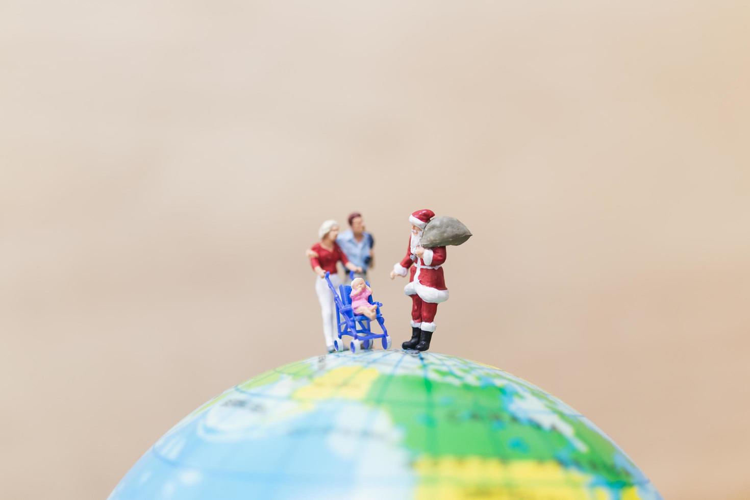 Babbo Natale in miniatura con regali per bambini su un globo, concetto di buon Natale foto
