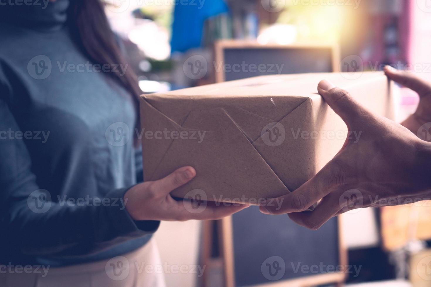 primo piano della donna che riceve una scatola o un pacco avvolto normale dalle due mani di un uomo foto