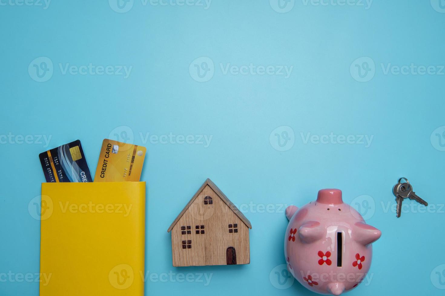 chiavi, salvadanaio, modello di casa e carte di credito su sfondo blu foto
