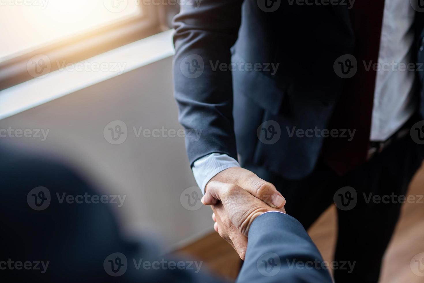primo piano di uomini d'affari si stringono la mano con sfondo sfocato foto