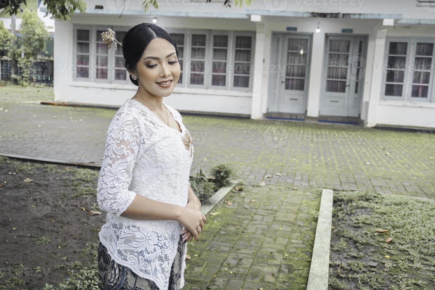 un' giovane indonesiano donna con un' contento riuscito espressione indossare un' bianca kebaya. di Kartini giorno concetto. foto