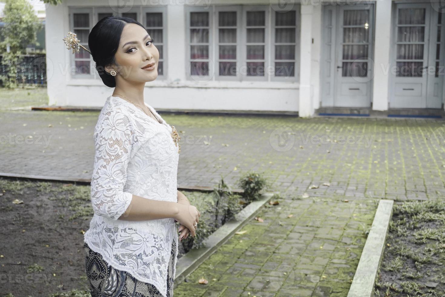 un' giovane indonesiano donna con un' contento riuscito espressione indossare un' bianca kebaya. di Kartini giorno concetto. foto