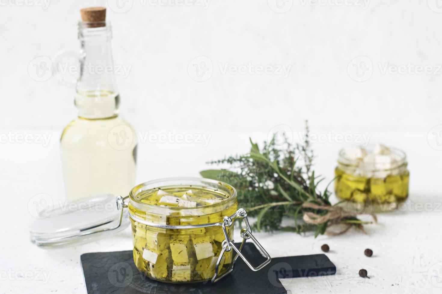 feta marinata in un barattolo di vetro, spezie e olio d'oliva aromatizzato su uno sfondo di legno foto