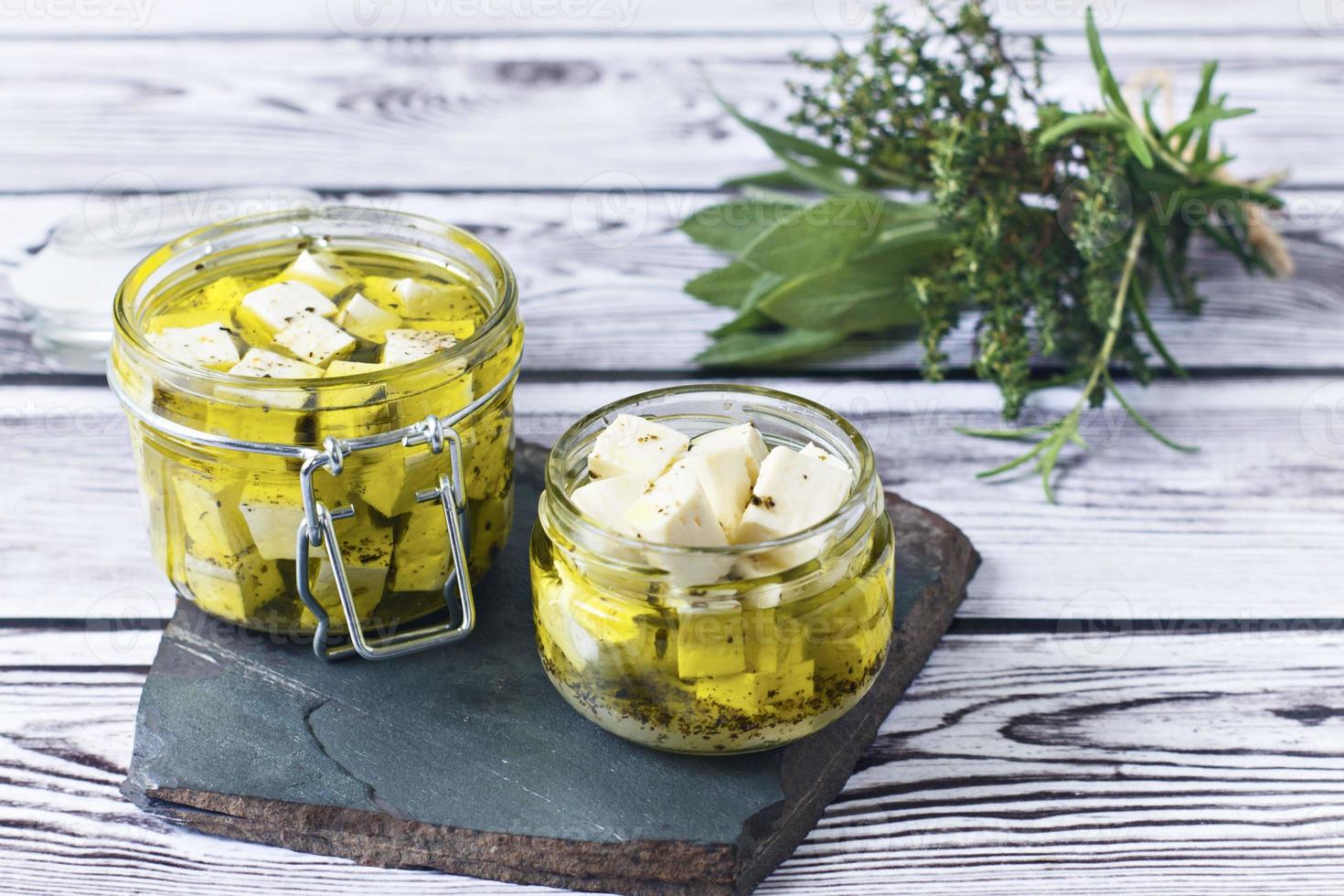 feta marinata in un bagno di vetro su uno sfondo di legno foto