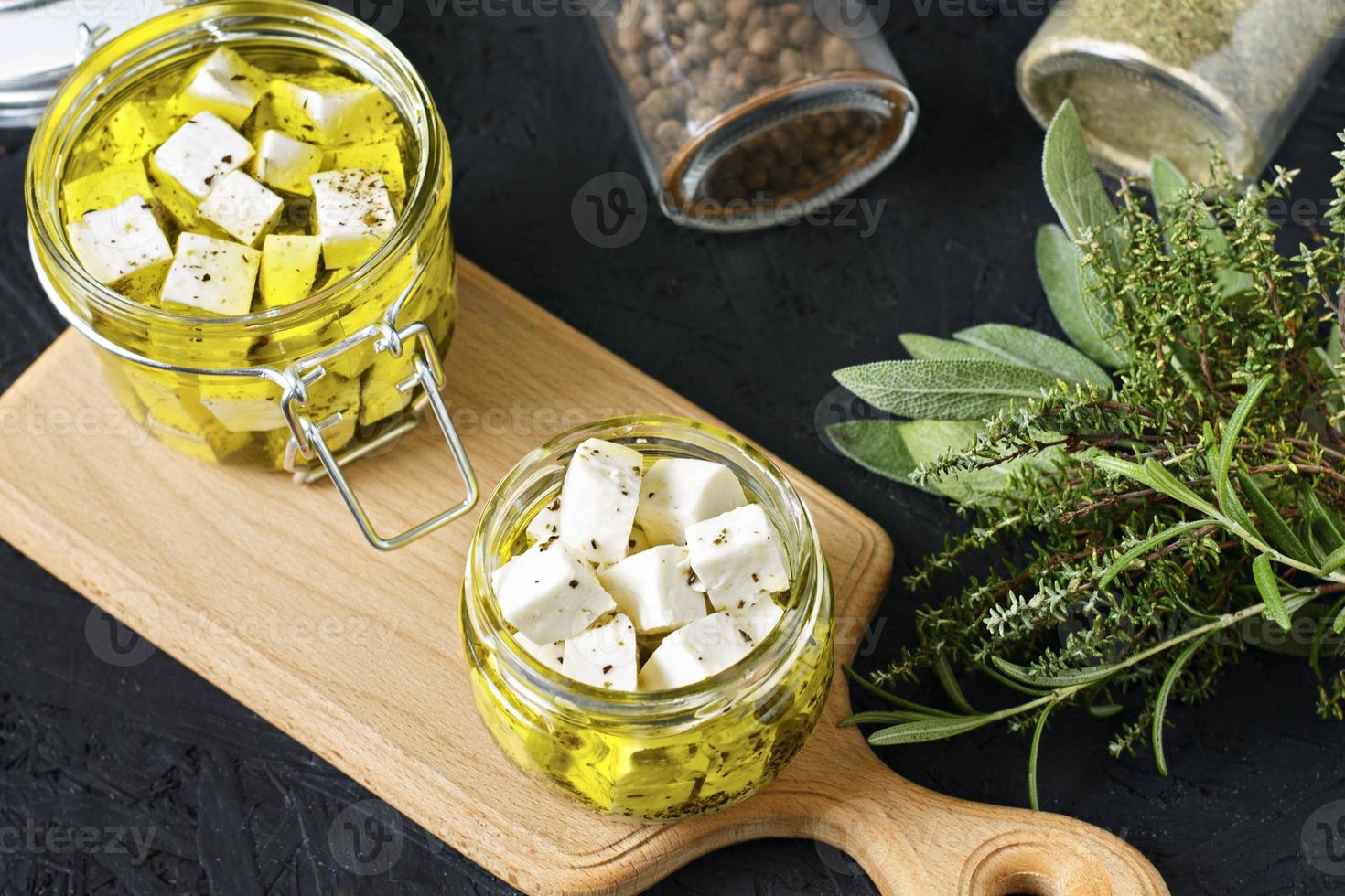 feta marinata in un barattolo di vetro e spezie su uno sfondo nero foto