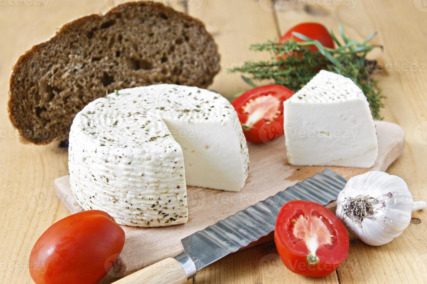 formaggio bianco, pane, pomodori e aglio su uno sfondo di legno foto