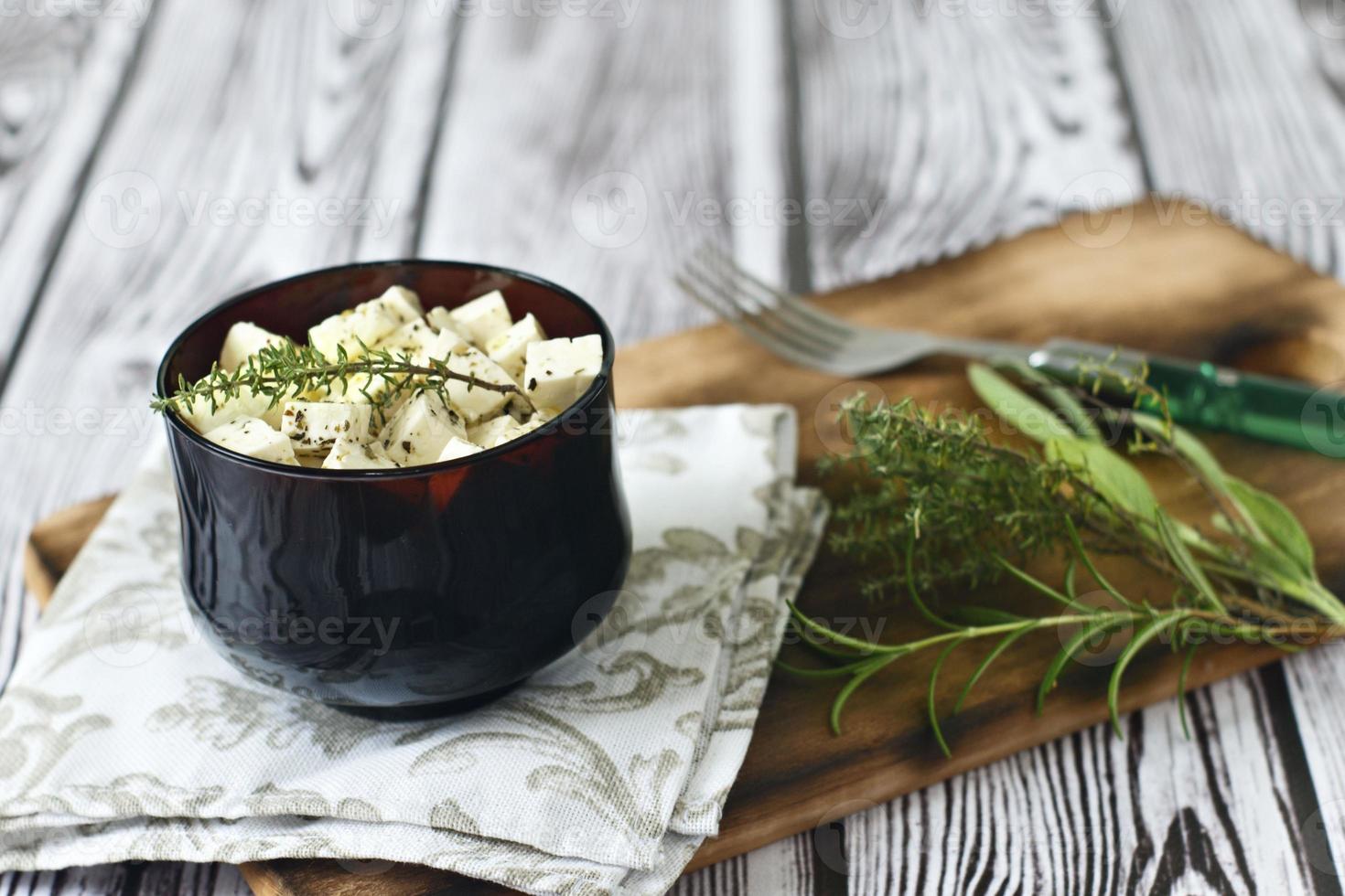 feta marinata in un piatto su una tavola di legno su uno sfondo di legno foto