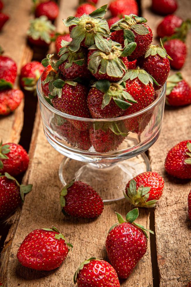 fragole in un bicchiere e su un tavolo foto