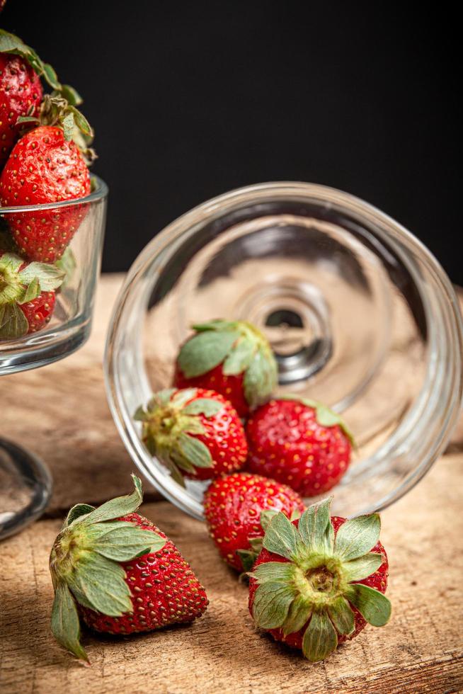 fragole in un bicchiere su un tavolo di legno foto