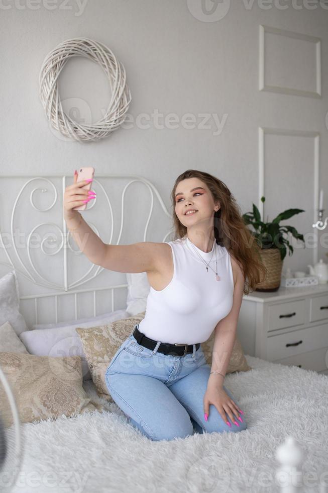 un' contento donna ha un' autoscatto. il ragazza sembra in il Telefono telecamera e sorrisi. foto