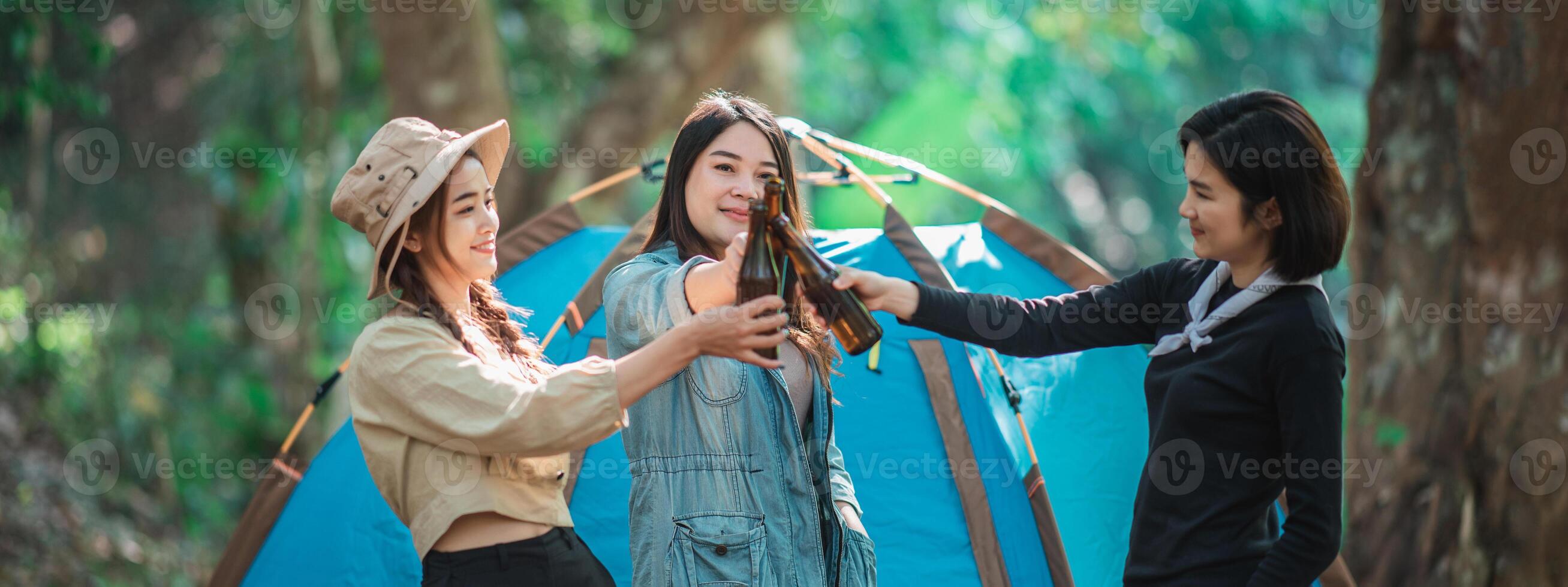 giovane donne rallegrare e bevanda bevanda davanti di campeggio tenda foto