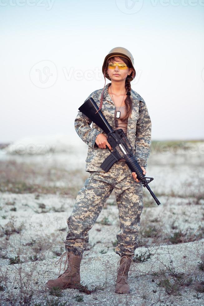 giovane femmina soldato vestito nel un' camuffare con un' pistola nel il all'aperto foto