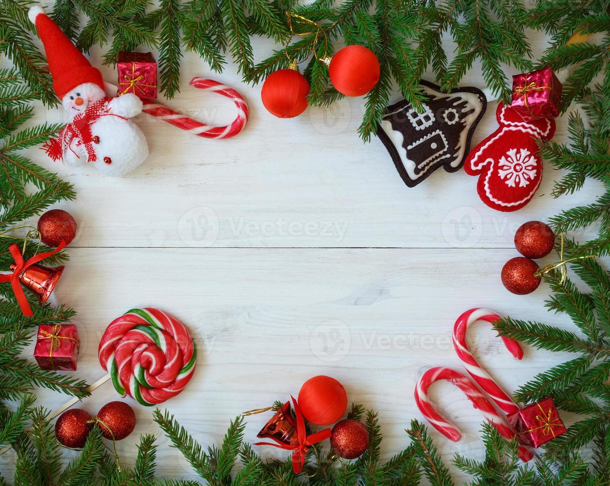 Natale confine con abete albero rami, Natale decorazioni e caramella canna su bianca di legno tavole foto