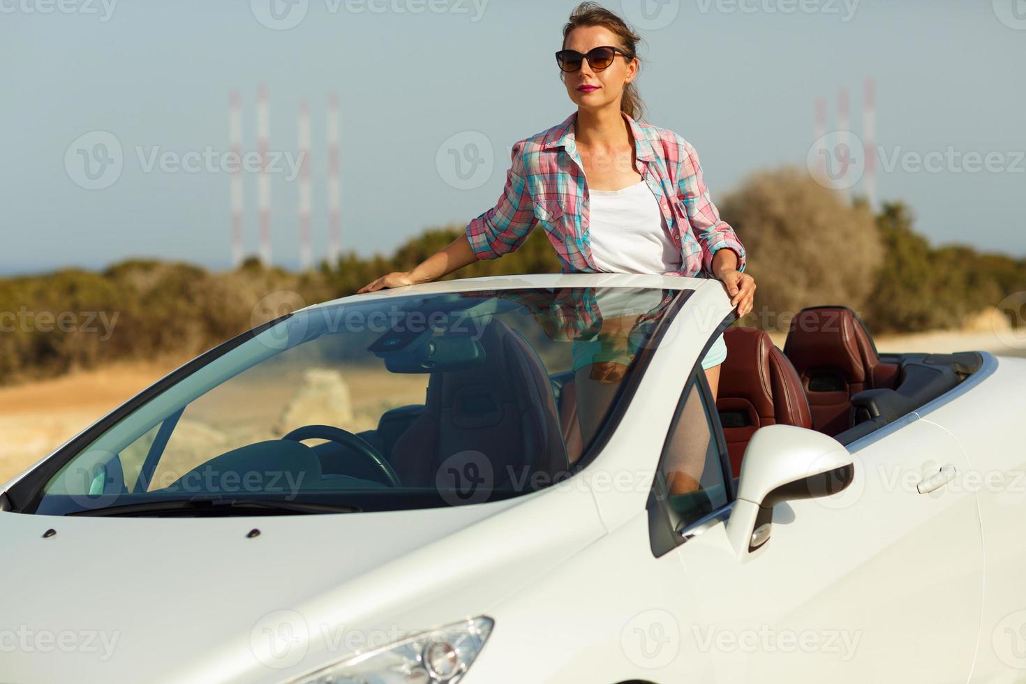 bellissimo donna seduta nel cabriolet, godendo viaggio su lusso moderno auto con Aperto tetto foto