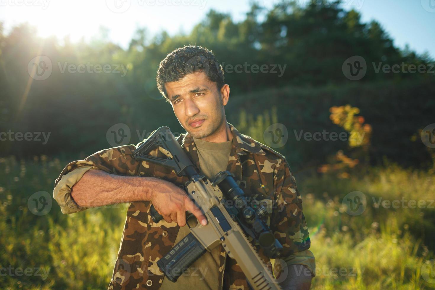 uomo di arabo nazionalità nel camuffare con un' fucile da caccia foto