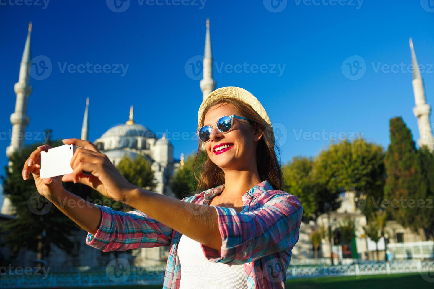 ragazza nel il cappello fabbricazione autoscatto di il smartphone su il sfondo di il blu moschea, Istanbul foto
