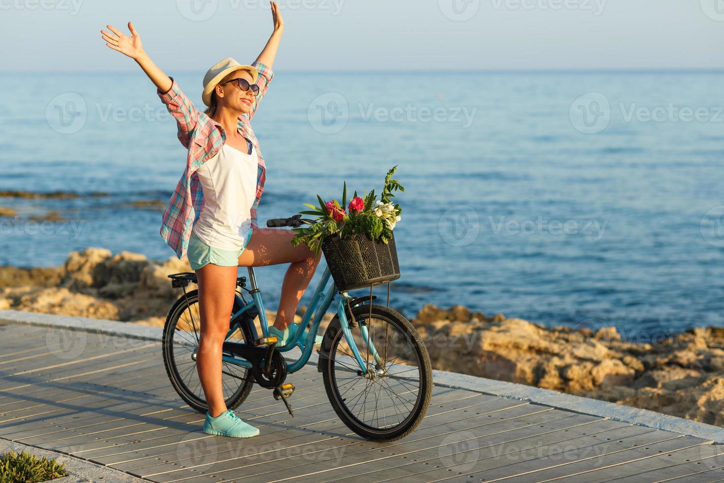 spensierato donna con bicicletta equitazione su un' di legno sentiero a il mare, avendo divertimento e sorridente foto