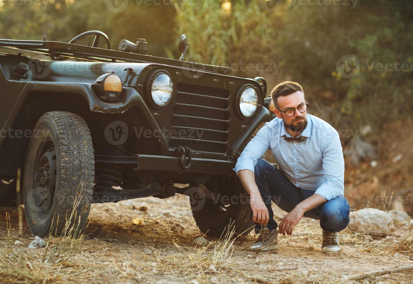 giovane elegante uomo con bicchieri e arco cravatta vicino il vecchio stile suv foto