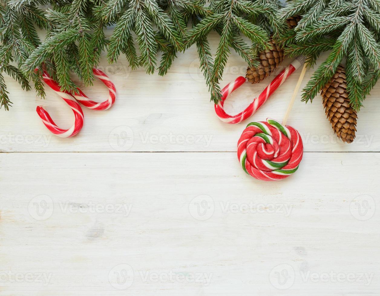 Natale confine con abete albero rami con coni e caramella canna su bianca di legno tavole foto