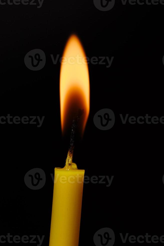 candela accesa su sfondo nero. lume di candela. la fiamma della candela. foto