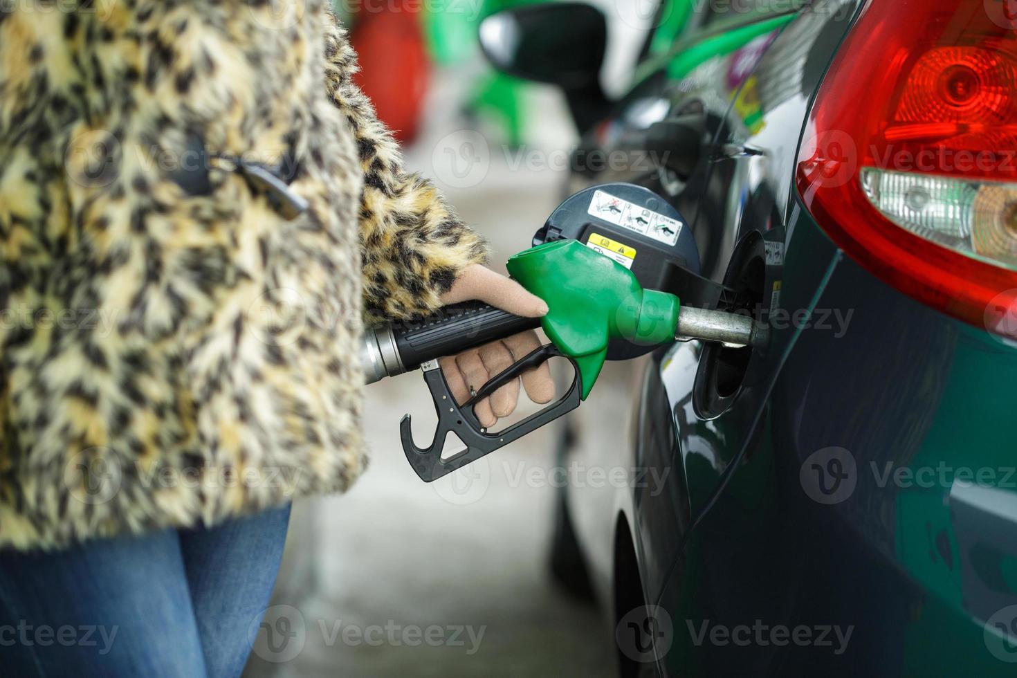 donna riempimenti benzina in sua auto a un' gas stazione nel inverno foto