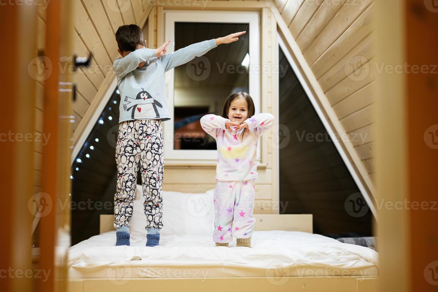 bambini nel morbido caldo pigiama giocando a di legno cabina casa. concetto di infanzia, tempo libero attività, felicità. fratello e sorella avendo divertimento e giocando insieme. foto