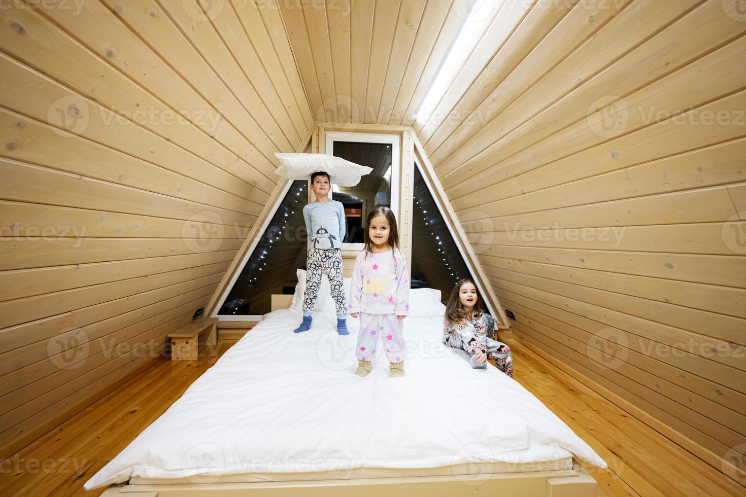 bambini nel morbido caldo pigiama giocando a di legno cabina casa. concetto di infanzia, tempo libero attività, felicità. fratello e sorelle avendo divertimento e giocando insieme. foto